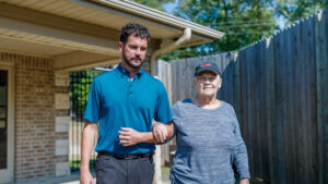 A man is walking with a resident at a skilled nursing facility with respite care